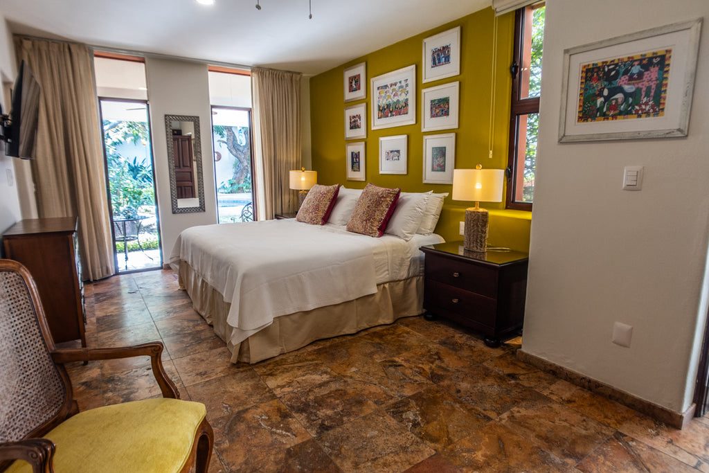 Neatly arranged bedroom with a bed, chairs, and wall art.