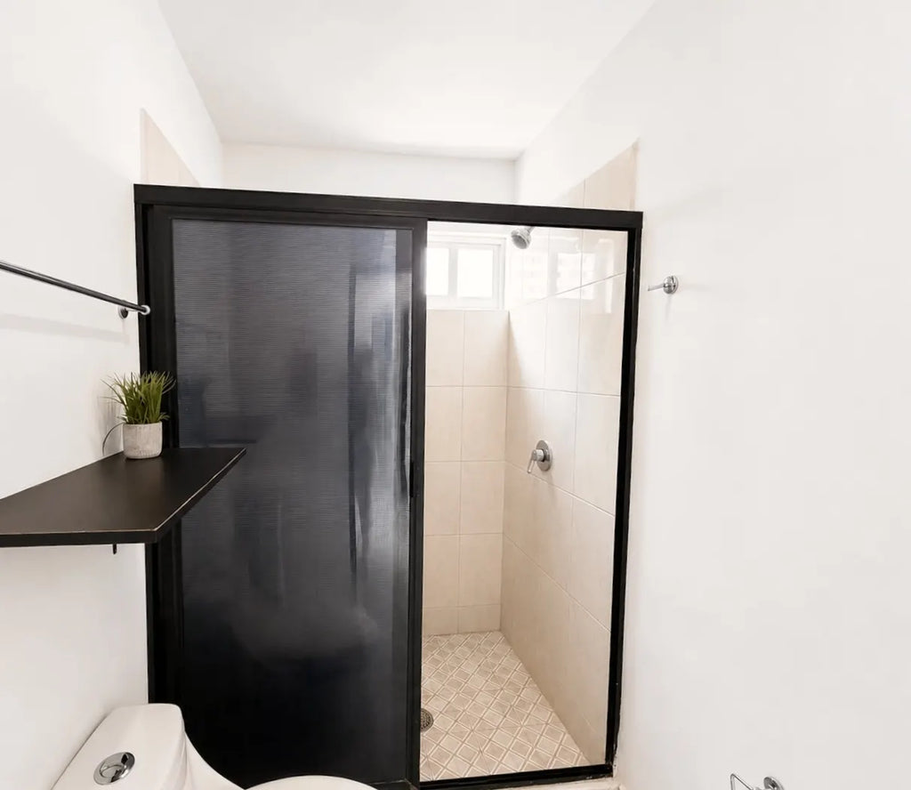 Baño con regadera y acabados en tonos oscuros, Mazatlán