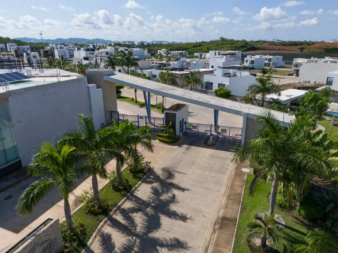 Acceso techado con palmeras y barda perimetral del fraccionamiento Pacífico Hills en Mazatlán