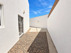 Patio lateral con acabado de piedra y acceso a la entrada de la casa