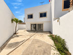Vista trasera de la casa de dos niveles con patio y acceso lateral