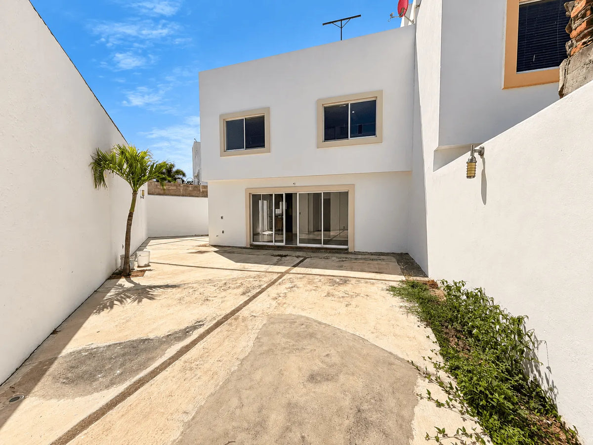 Vista trasera de la casa de dos niveles con patio y acceso lateral