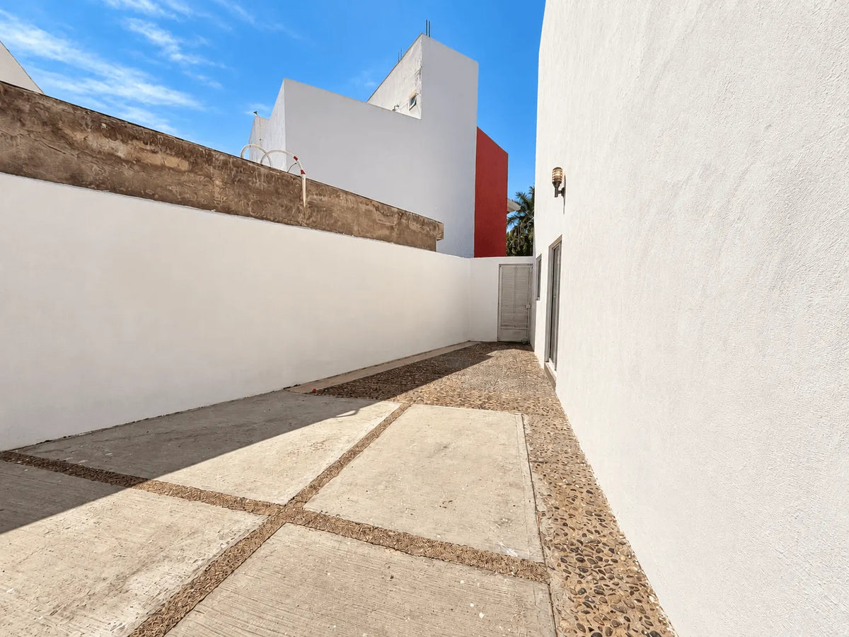 Pasillo lateral exterior de la casa con piso adoquín