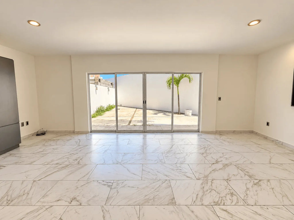 Sala amplia con piso de mármol y puerta corrediza hacia el patio