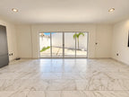 Sala amplia con piso de mármol y puerta corrediza hacia el patio
