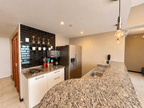 Cocina amueblada con azulejo negro, refrigerador y barra de granito en departamento en venta en Park Royal Mazatlán