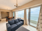 Sala con sofá oscuro y puertas corredizas hacia la terraza con vista al mar en Park Royal Mazatlán