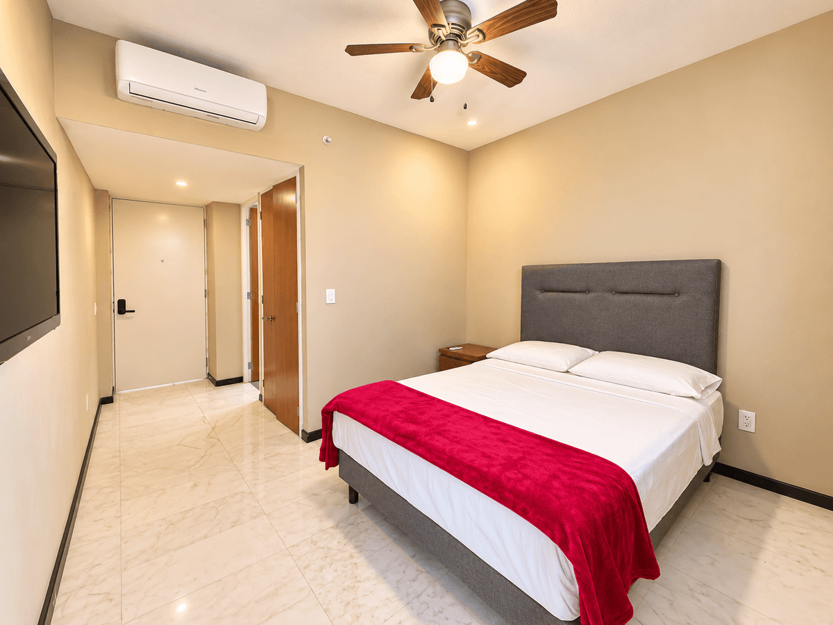 Habitación con aire acondicionado, TV y cobertor rojo, ideal para renta vacacional en Park Royal Mazatlán