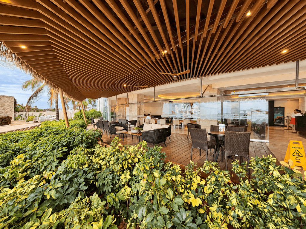 Área de restaurante con terraza y techo de madera rodeada de jardín en el edificio Park Royal Mazatlán