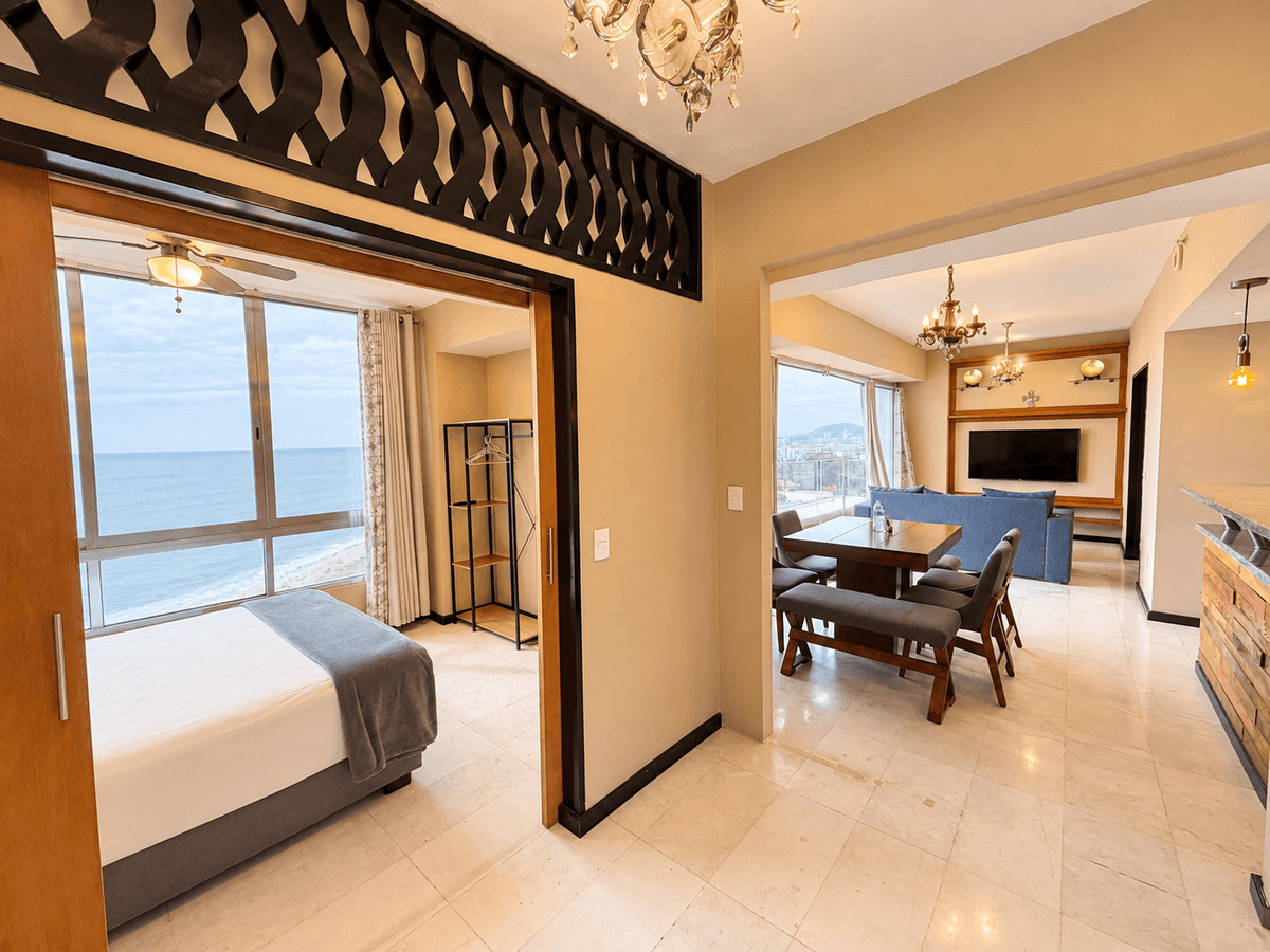 Recámara con puerta corrediza abierta hacia sala y comedor con vista al mar en Park Royal Mazatlán