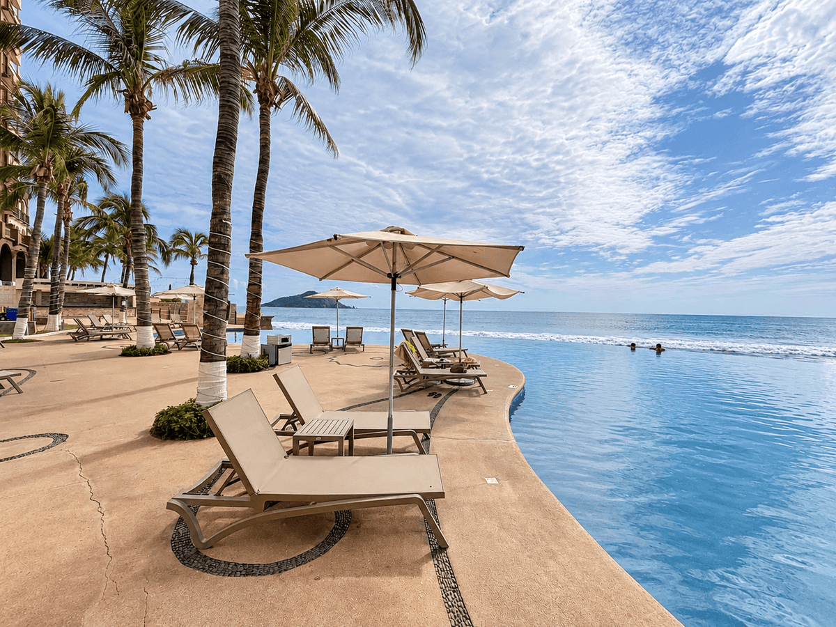 Alberca infinita con camastros y palmeras junto a la playa en Park Royal Mazatlán, Cerritos
