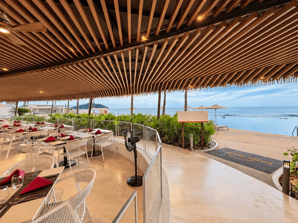 Restaurante con terraza abierta frente a la playa y techo de madera en el edificio Park Royal Mazatlán