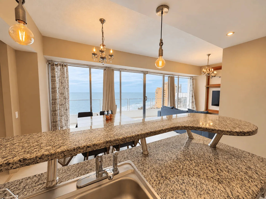 Barra de granito con fregadero y ventanales con vista al mar en la cocina de un departamento en Park Royal Mazatlán