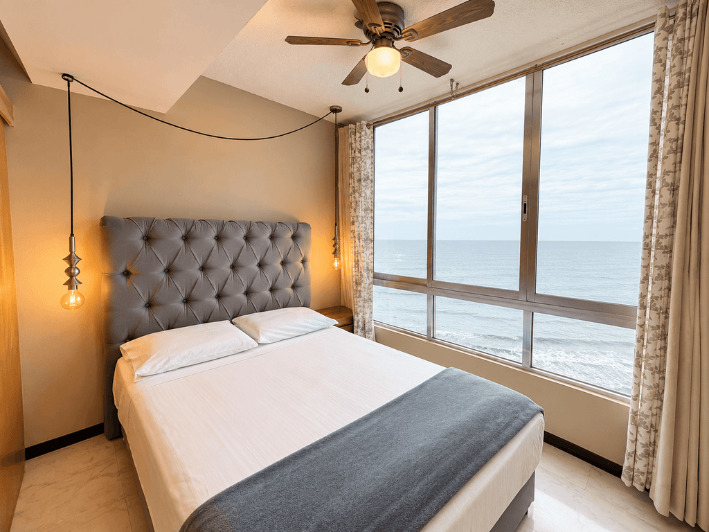 Recámara con cabecera capitoné y ventanal con vista al mar en departamento en Park Royal Mazatlán