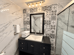 Baño con muros de mármol, mosaico decorativo y regadera de cristal en departamento en Park Royal Mazatlán