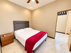 Recámara con cama matrimonial, cobertor rojo y buró de madera en departamento en Park Royal Mazatlán