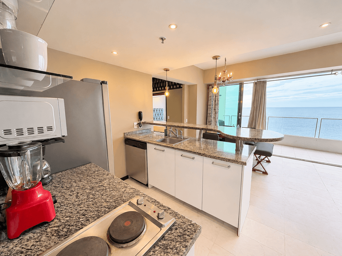 Cocina con barra de granito y ventanal con vista al mar en departamento en venta en Cerritos, Mazatlán