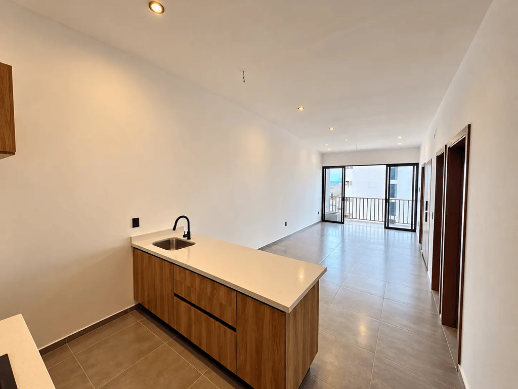 Cocina con barra y sala con ventanal al fondo, departamento a estrenar en Palos Prietos