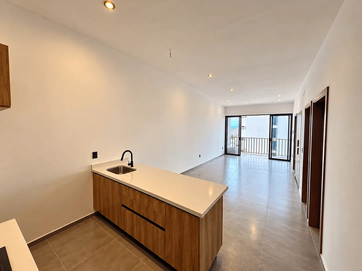 Cocina con barra y sala con ventanal al fondo, departamento a estrenar en Palos Prietos