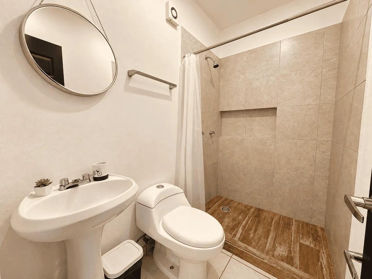 Baño con lavabo de pedestal, WC y regadera con cortina en departamento de 2 baños en venta en Azul Marino