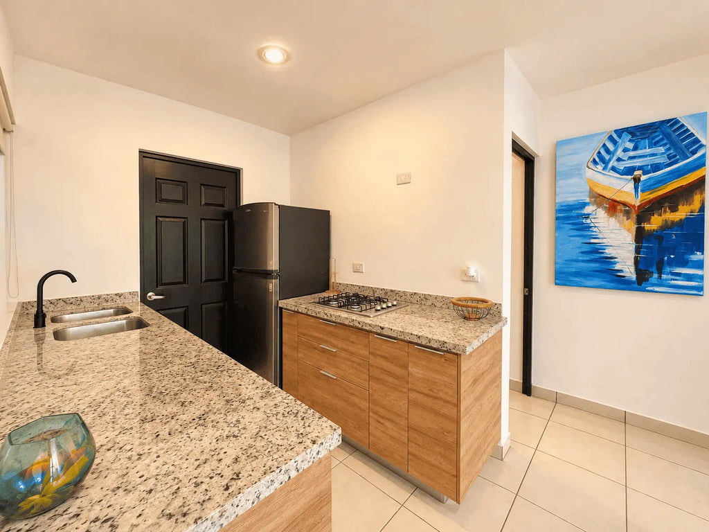 Cocina con fregadero, barra de granito y refrigerador en departamento amueblado en venta en Azul Marino