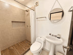 Baño completo con regadera, lavabo de pedestal y espejo redondo en departamento en venta en Cerritos, Mazatlán