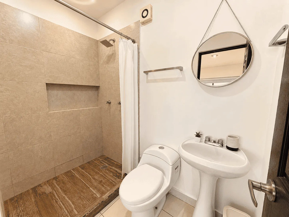 Baño completo con regadera, lavabo de pedestal y espejo redondo en departamento en venta en Cerritos, Mazatlán