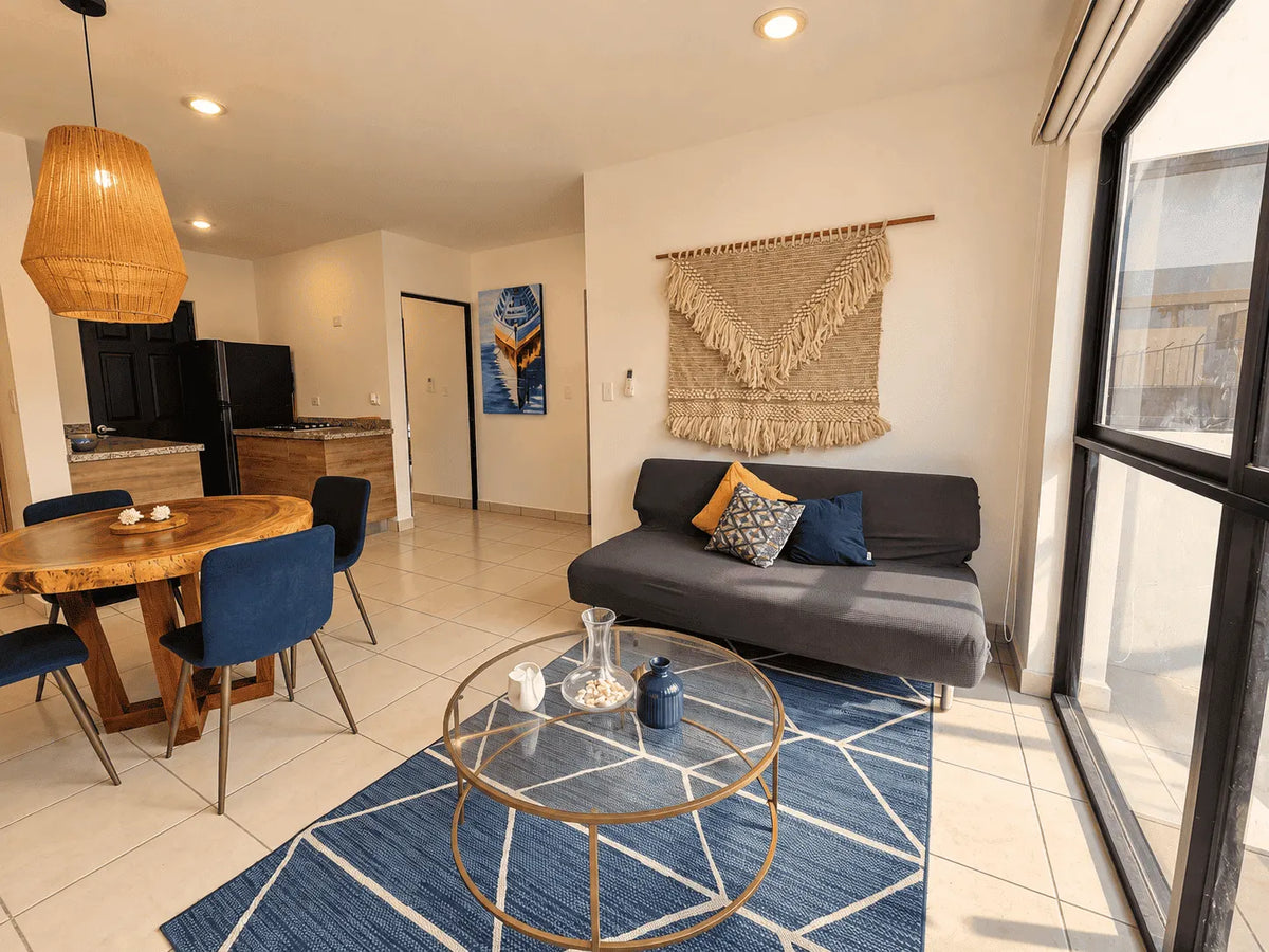 Sala con sofá, mesa de centro y comedor de madera en departamento amueblado en venta en Mazatlán