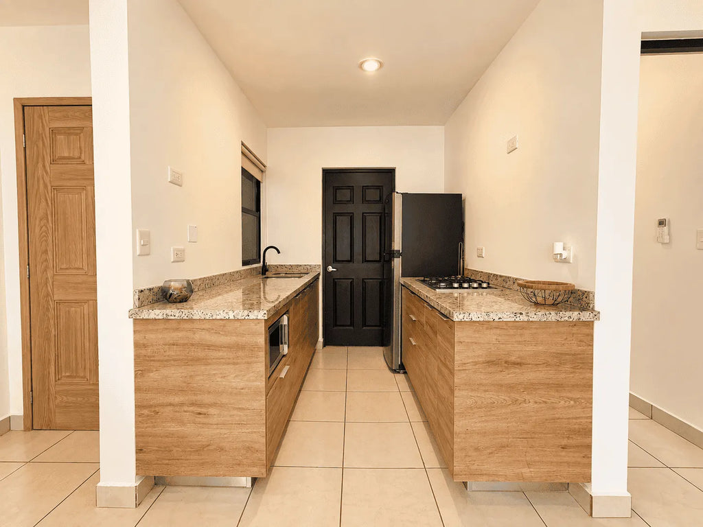 Vista frontal de la cocina equipada con barra de granito y refrigerador en departamento en venta en Cerritos