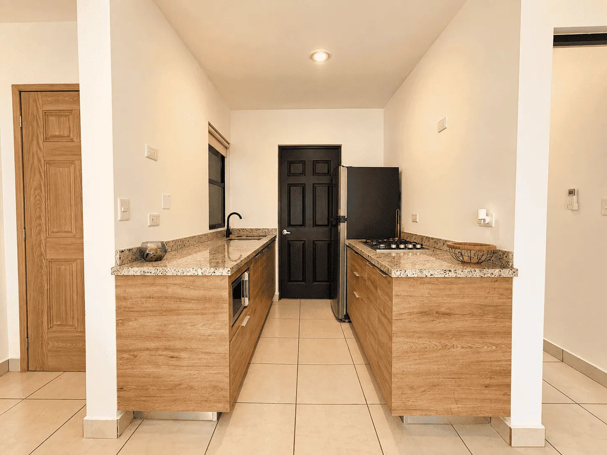 Vista frontal de la cocina equipada con barra de granito y refrigerador en departamento en venta en Cerritos