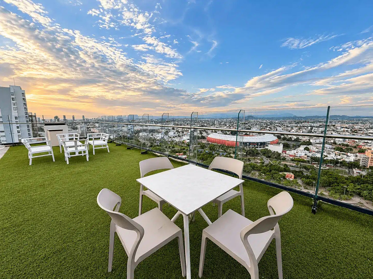 Terraza rooftop con mesas y vista a la ciudad al atardecer, Torre Central 102 Malecón Mazatlán