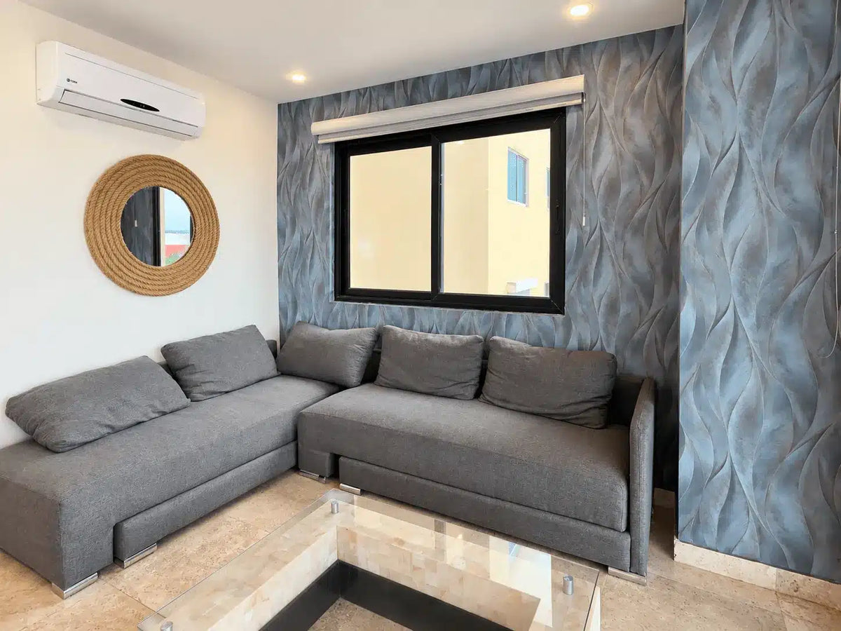 Sala con sofá gris y ventana con vista a la ciudad, Torre Central 102