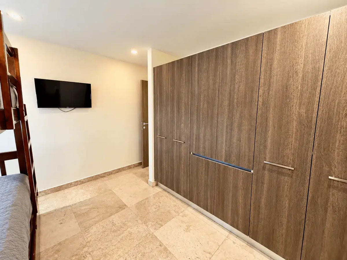 Pasillo con closets de madera y televisión, departamento en Torre Central 102 Mazatlán