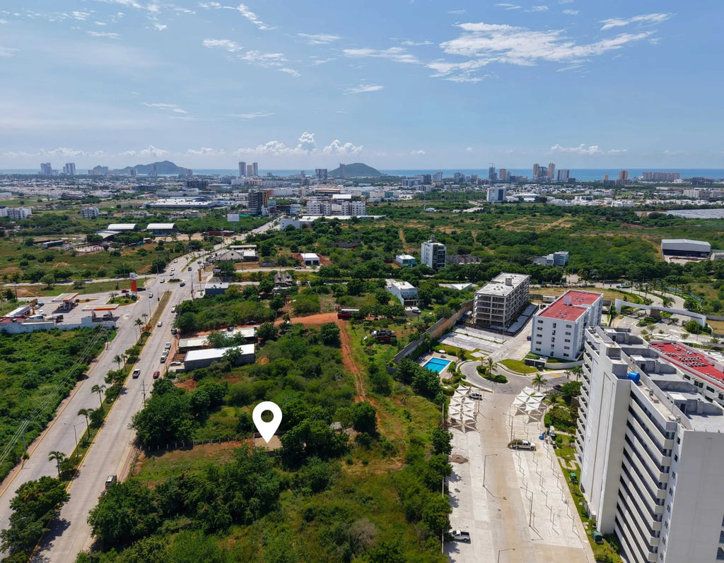Ubicación del terreno en venta en Marina Universidad, Mazatlán, señalada sobre vista aérea con edificios cercanos
