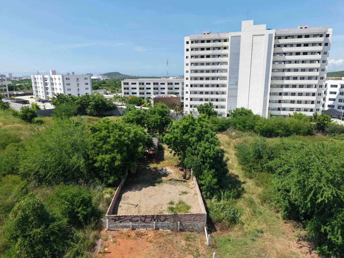 Terreno en Marina Universidad, Mazatlán, visto desde el aire junto a edificio residencial